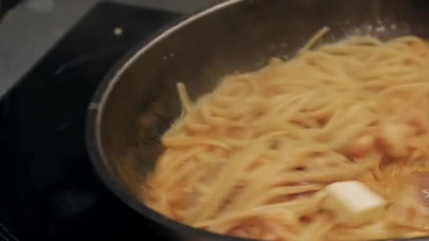 Chef stirs spaghetti with bacon in a frying pan — Stock Video