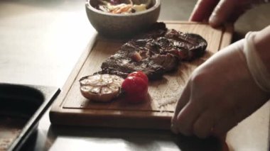 Restoran yemekleri, ahşap tahtada domatesli et dilimleri servis ediliyor.