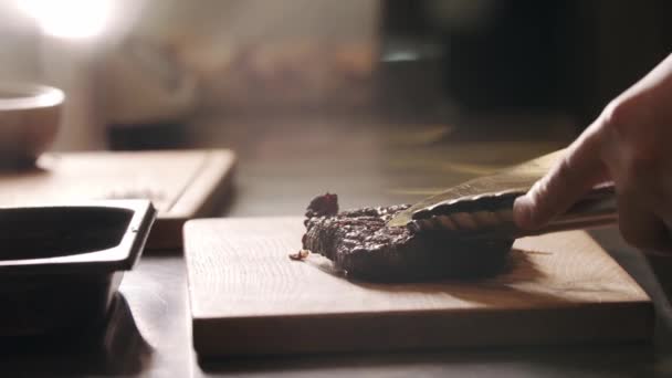 Ресторан приготовления пищи - шеф-повар режет кусок мяса с ножом на доске — стоковое видео