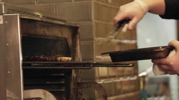 Restaurang matlagning - kocken tar ut en bit kött och torkade grönsaker från ugnen — Stockvideo