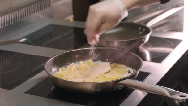 Restaurang matlagning - kock salter och paprika grädde pasta med svamp i en stekpanna — Stockvideo