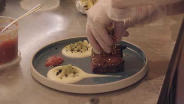 Cocina del restaurante - el chef sirve un pedazo de carne en un plato con un plato al lado de la papa — Vídeos de Stock