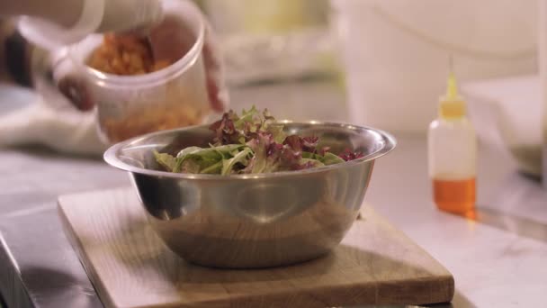 Restaurant koken - chef voegt pompoenstukjes toe aan sla bladeren in een kom — Stockvideo