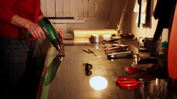 Krejčí zahřívá kus kůže na opasek v jeho osobní dílně — Stock video