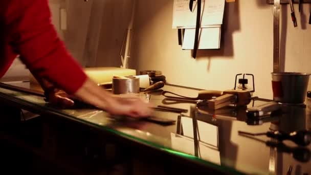 En mand polerer et stykke læder til bæltet i sit personlige værksted – Stock-video