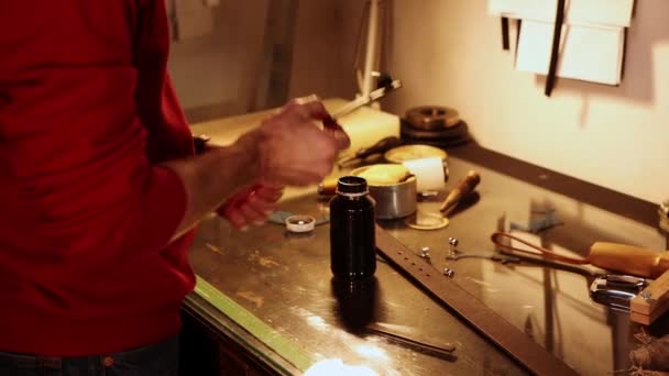 Laboratorio in pelle - un uomo che dipinge il pezzo di pelle con uno strumento speciale — Video Stock