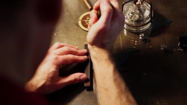 Kožená dílna - muž stříhá kus lisované kůže horkým pájkou — Stock video