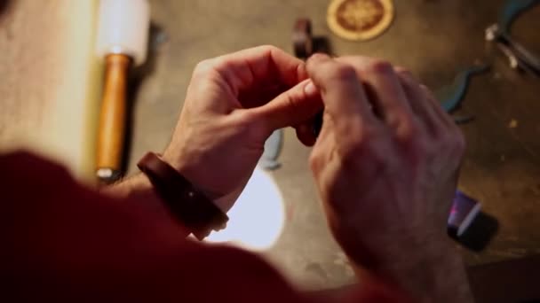 Taller de cuero: un hombre cose un lazo de cinturón con una aguja gruesa — Vídeos de Stock