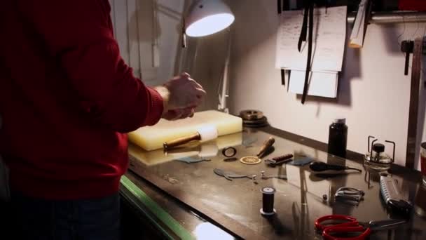 Lederwerkstatt - ein Mann poliert Kanten einer Gürtelschlaufe — Stockvideo