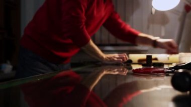 Deri atölyesi - bir adam masanın yanında bir bez parçasıyla kemeri ovuyor