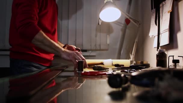 Lederwerkstatt - ein Mann poliert Kanten einer Ledergürtelschlaufe — Stockvideo