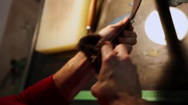 Læder workshop - en mand gnider et bælte med en klud – Stock-video