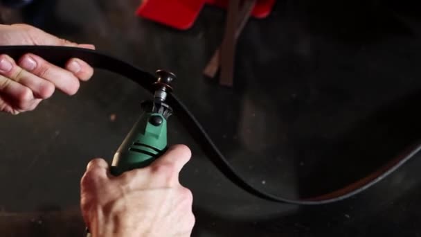 Oficina de couro - um homem retifica as bordas de um cinto de couro usando uma ferramenta — Vídeo de Stock