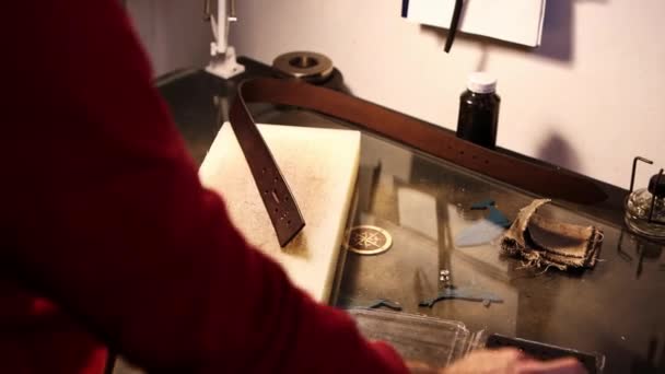 Kožená dílna - muž, který vyrábí opasek z lisované kůže — Stock video