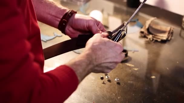 Læder workshop en mand skruer et spænde til et læderbælte – Stock-video