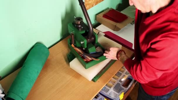 Taller de cuero: un hombre corta una pieza de cuero en forma de árbol de Navidad con un sello y una prensa eléctrica — Vídeos de Stock