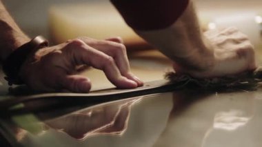 Bir adam deri kemeri paçavra ile parlatıyor.