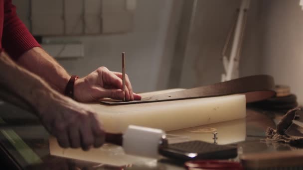 テーブルによって革ベルトの男パンチ穴 — ストック動画