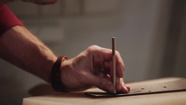 Um homem faz buracos em um cinto de couro — Vídeo de Stock