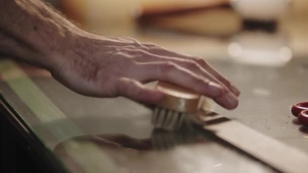En mand polerer læderbæltet ved hjælp af en børste – Stock-video