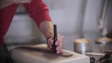 Terzi enstrüman kullanarak deri parçasına küçük delikler açıyor.