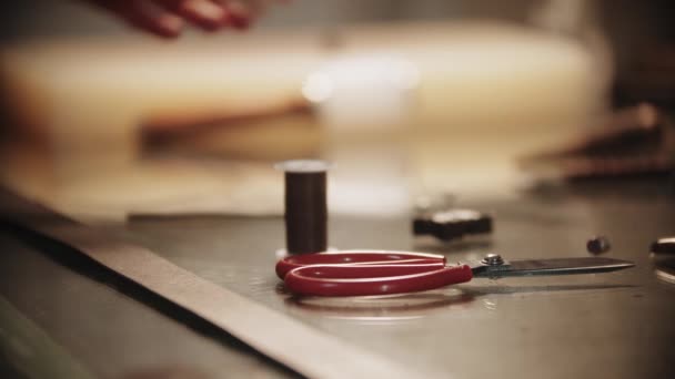 A man makes a leather belt - needle and thread with scissors in the foreground — Stock Video
