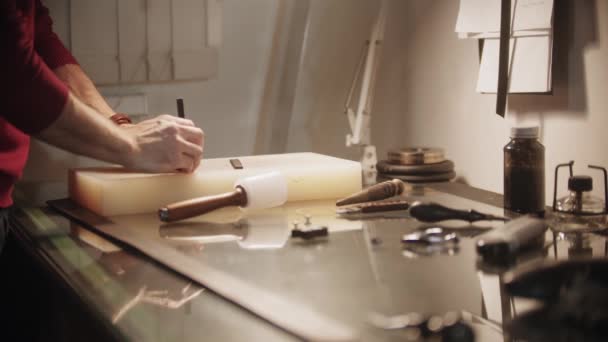 Schneider macht Löcher in ein kleines Stück Leder — Stockvideo