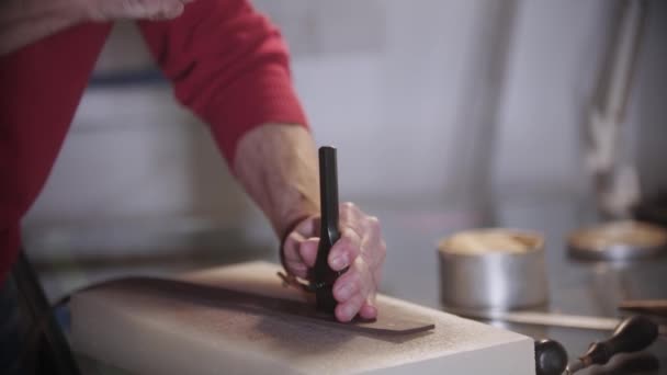 재단사는 악기를 사용하여 가죽 조각에 작은 구멍을 내 놓는다 — 비디오