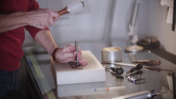 Um homem despeja pequenos buracos no pedaço de couro usando instrumentos — Vídeo de Stock
