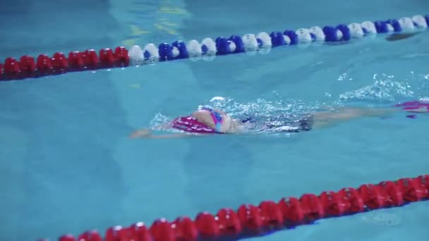 25-15-2021 RUSIA, KAZAN - COMPETICIONES DE Nadar - una niña nada sobre su espalda a lo largo de la pista usando sus piernas — Vídeos de Stock