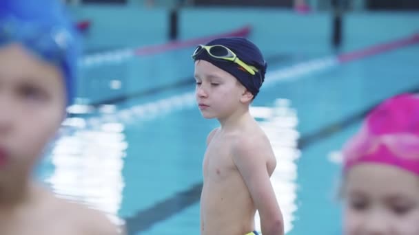 25-15-2021 RUSSLAND, KASAN - SCHWIMMENWETTBEWERB - Ein kleiner Junge am Pool betrachtet andere Teilnehmer — Stockvideo