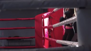 Genç kadın boks ringinde yürüyor.