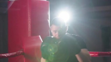 Genç bir adam ringde gölge boksu yapıyor.