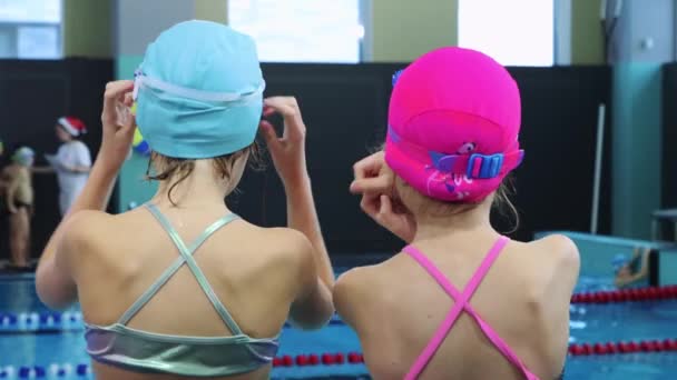 25-15-2021 RUSIA, KAZAN - COMPETICIONES DE Nadar - niñas pequeñas que se arreglan el cabello poniéndolo debajo del sombrero de baño — Vídeos de Stock
