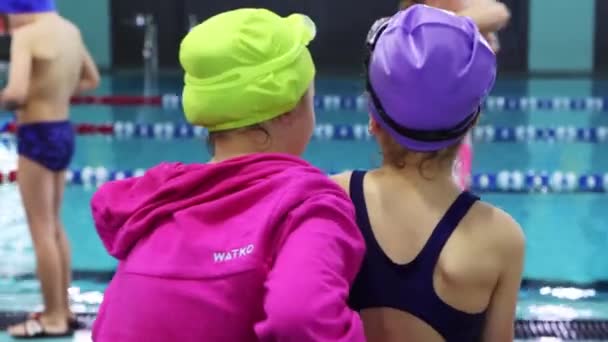 25-15-2021 RUSIA, KAZAN - COMPETICIONES DE Nadar - niñas sentadas en el banco junto a la piscina y abrazadas — Vídeos de Stock