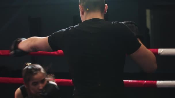 Mujer joven entrenando esquivando con su entrenador masculino en el ring de boxeo — Vídeos de Stock