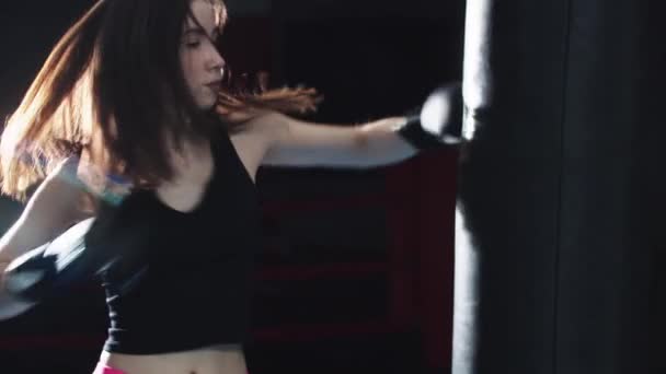 Mujer joven golpeando el saco de boxeo — Vídeo de stock