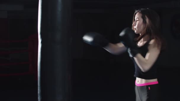 Mladá žena bít boxovací pytel na boxerském ringu — Stock video