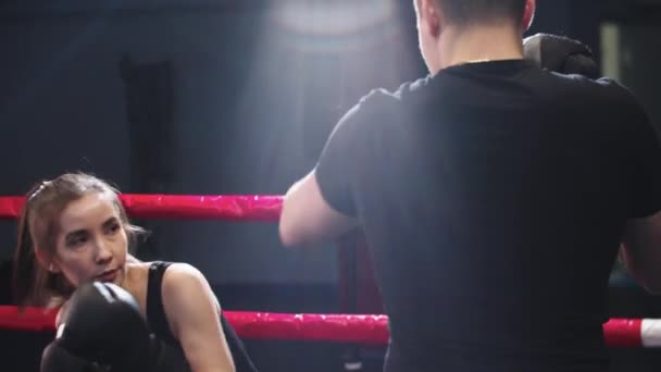 Mujer joven con pelo largo entrenamiento boxeo con su entrenador personal en el anillo — Vídeo de stock