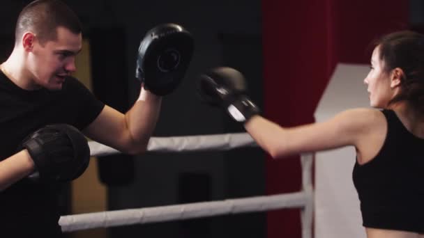 Mujer joven con pelo largo entrenamiento boxeo con su entrenador masculino personal en el ring - golpeando y esquivando — Vídeos de Stock