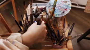 Sanat stüdyosu - kadın sanatçı palette renk karıştırıyor ve resim çiziyor