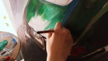 Sanat stüdyosu - kadın sanatçı yeşil ve mavi renkler kullanarak bir resim çiziyor