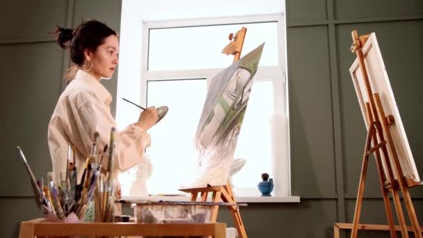 Atelier d'art - jeune femme en chemise blanche tachée dessinant une peinture — Video