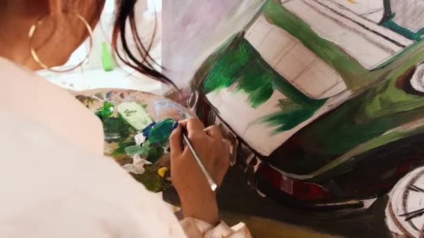 Art studio - νεαρή γυναίκα με λευκό πουκάμισο ανακατεύοντας χρώματα στην παλέτα και ζωγραφίζοντας έναν πίνακα — Αρχείο Βίντεο
