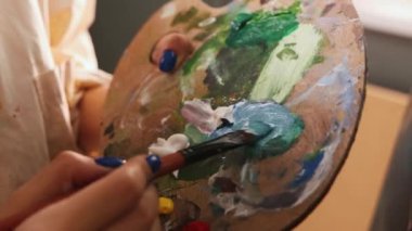 Sanat stüdyosu - kadın sanatçı palette renkleri karıştırıyor