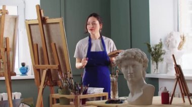 Gülümseyen kadın ressam resmini bitirir ve ona bakar.