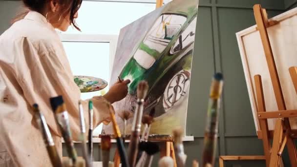 Studio d'arte - artista donna che disegna un'auto sulla tela — Video Stock