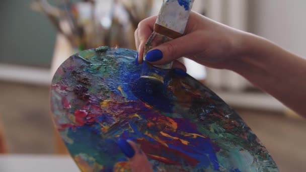 Une artiste femme mélangeant des peintures bleues sur la palette — Video