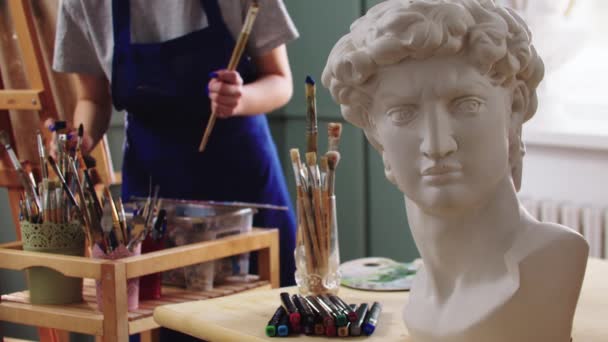 Жінка-художник вибирає пензлі з баночки - мармурова скульптура на передньому плані — стокове відео
