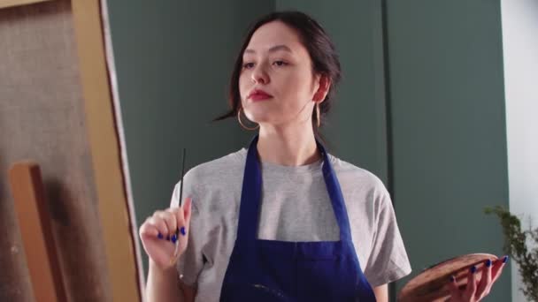 Bella artista donna che disegna un dipinto su tela utilizzando pennelli — Video Stock